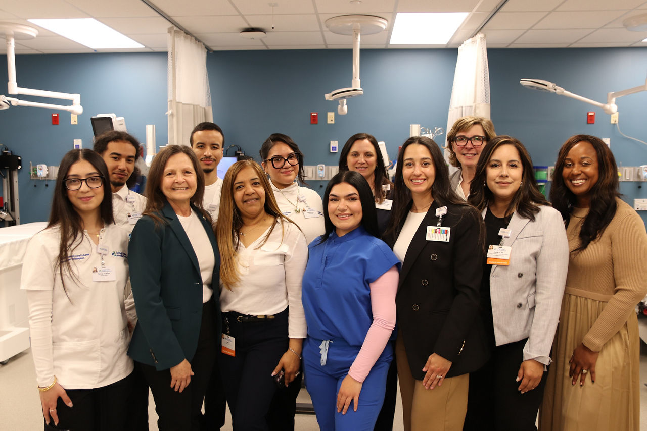 L and I Secretary Nancy A. Walker stands with a group of ten people, including healthcare students and professionals in uniform, smile warmly in a medical facility, conveying teamwork and positivity.