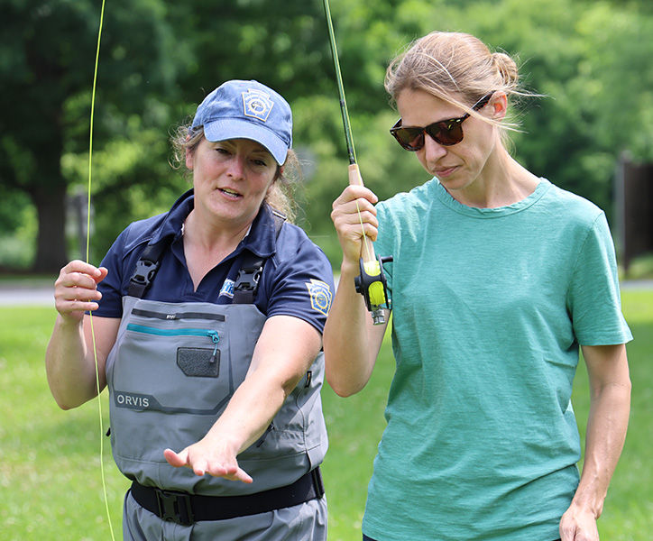 PFBC Educator teaches a woman how to cast a fly fishing rod