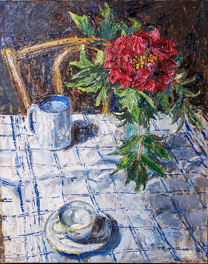 a peony in a vase with a white tablecloth and dishes