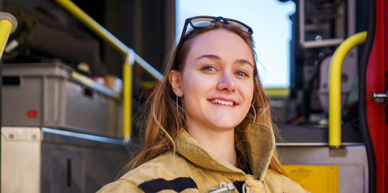 A young girl wears firefighter gear.