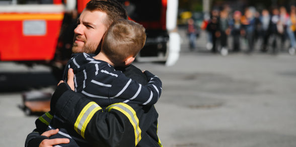 image of firefighter hugging a child