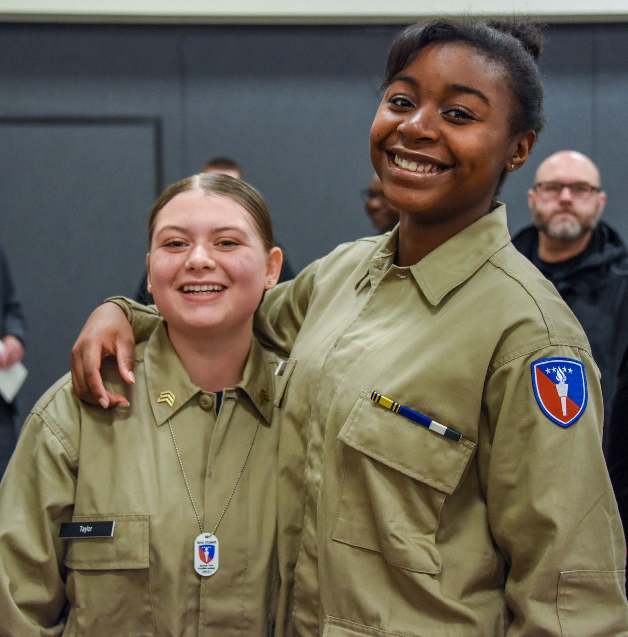 Two cadets standing together smiling in military style uniforms.