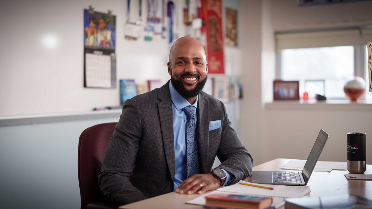 Leon Smith sitting at a desk in a classroom smiling.