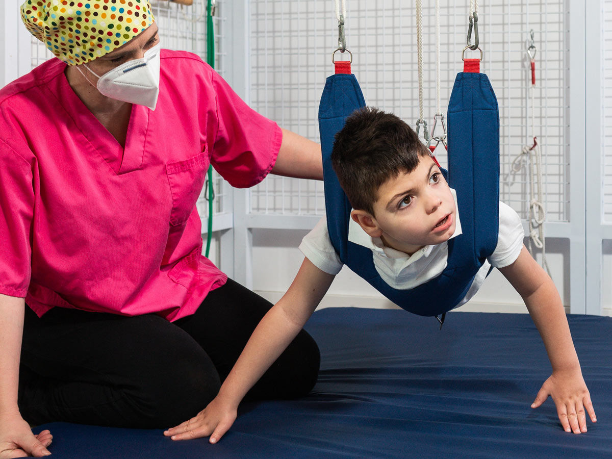Child in therapy harness with caregiver