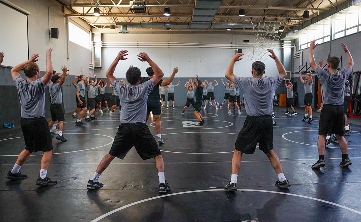 A large circle of Law and Leadership Academy cadets perform a jumping exercise in a gymnasium