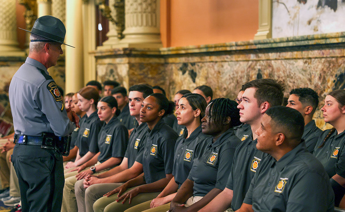 A State Trooper addresses a row of seated Law and Leadership Academy  cadets