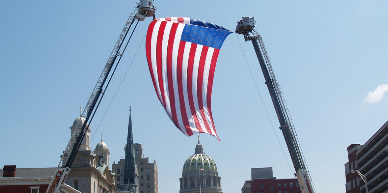 A flag is raised by fire apparatuses in front of the state Capitol.