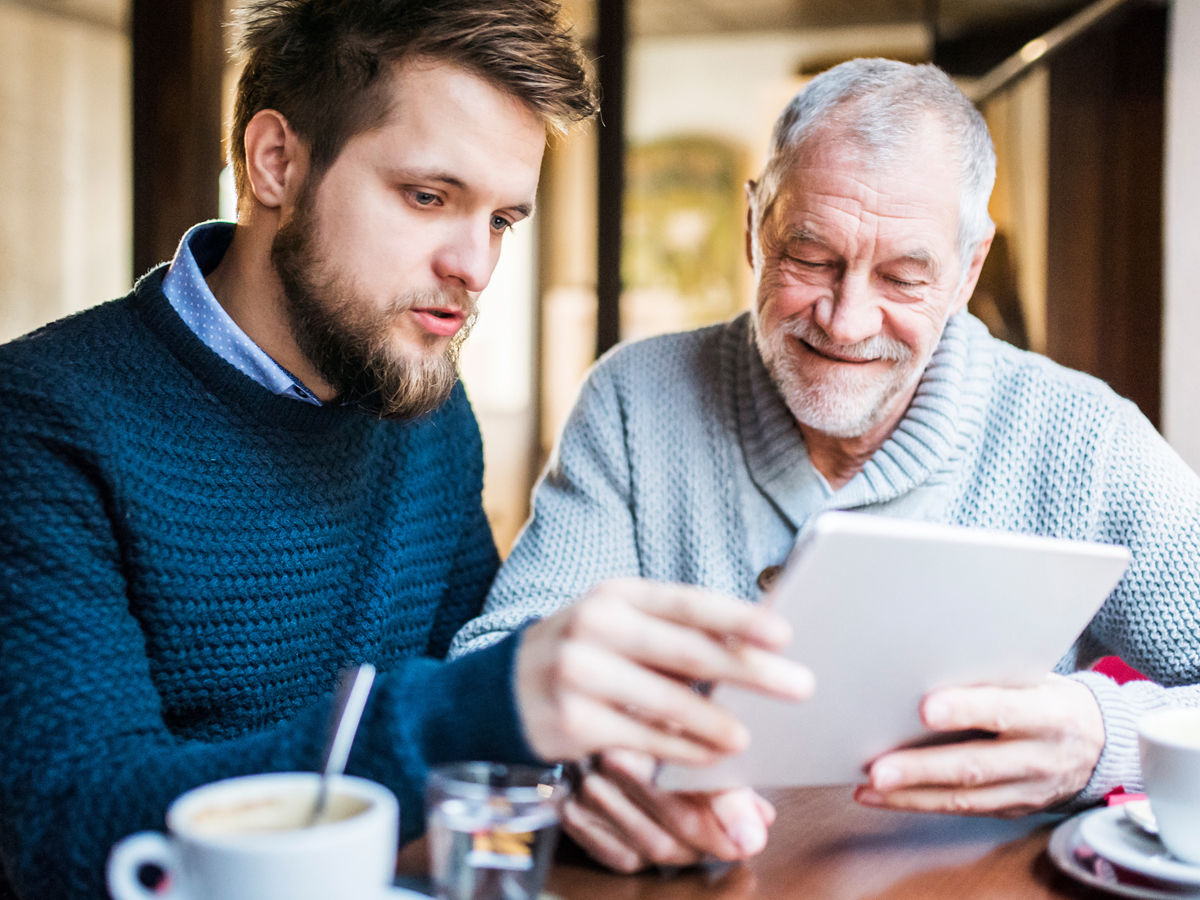 younger man helping older man with a tablet