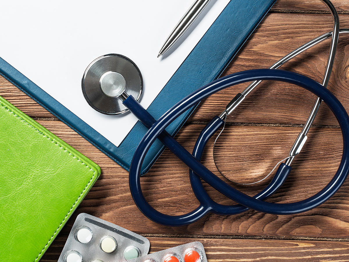 Doctors wooden table with tablet stethoscope and other medical items.