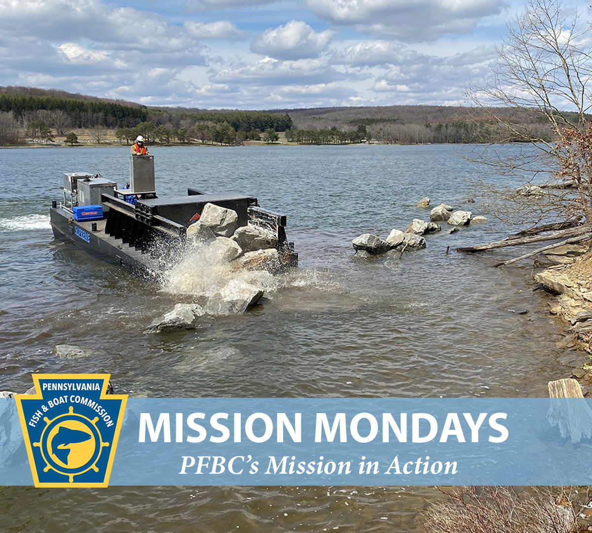 PFBC barge placing large boulders along a lakeshore with the PFBC logo and "Mission Mondays:  PFBC's Mission in Action" text shown.