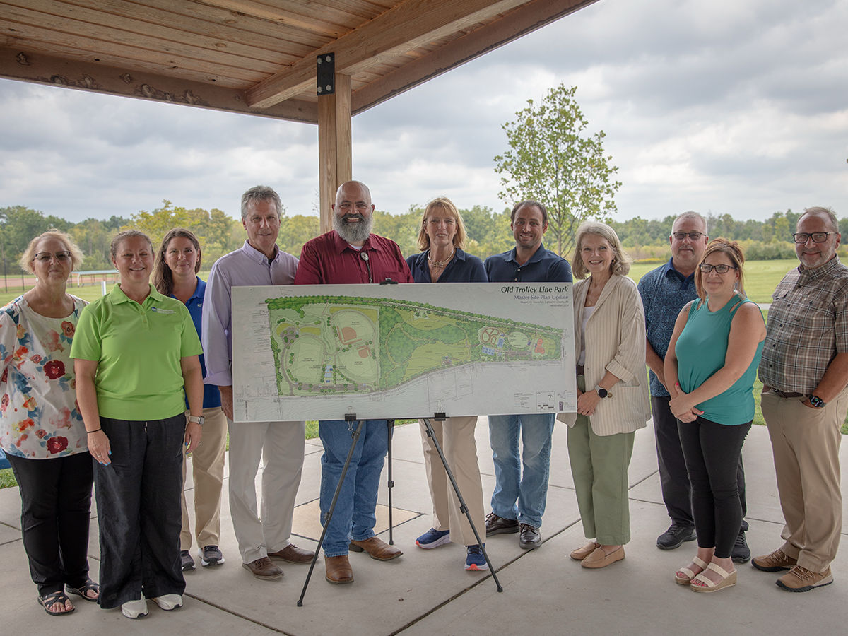 A group of people stand behind a large map.