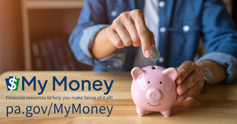 A person putting a quarter into a pink piggy bank. 