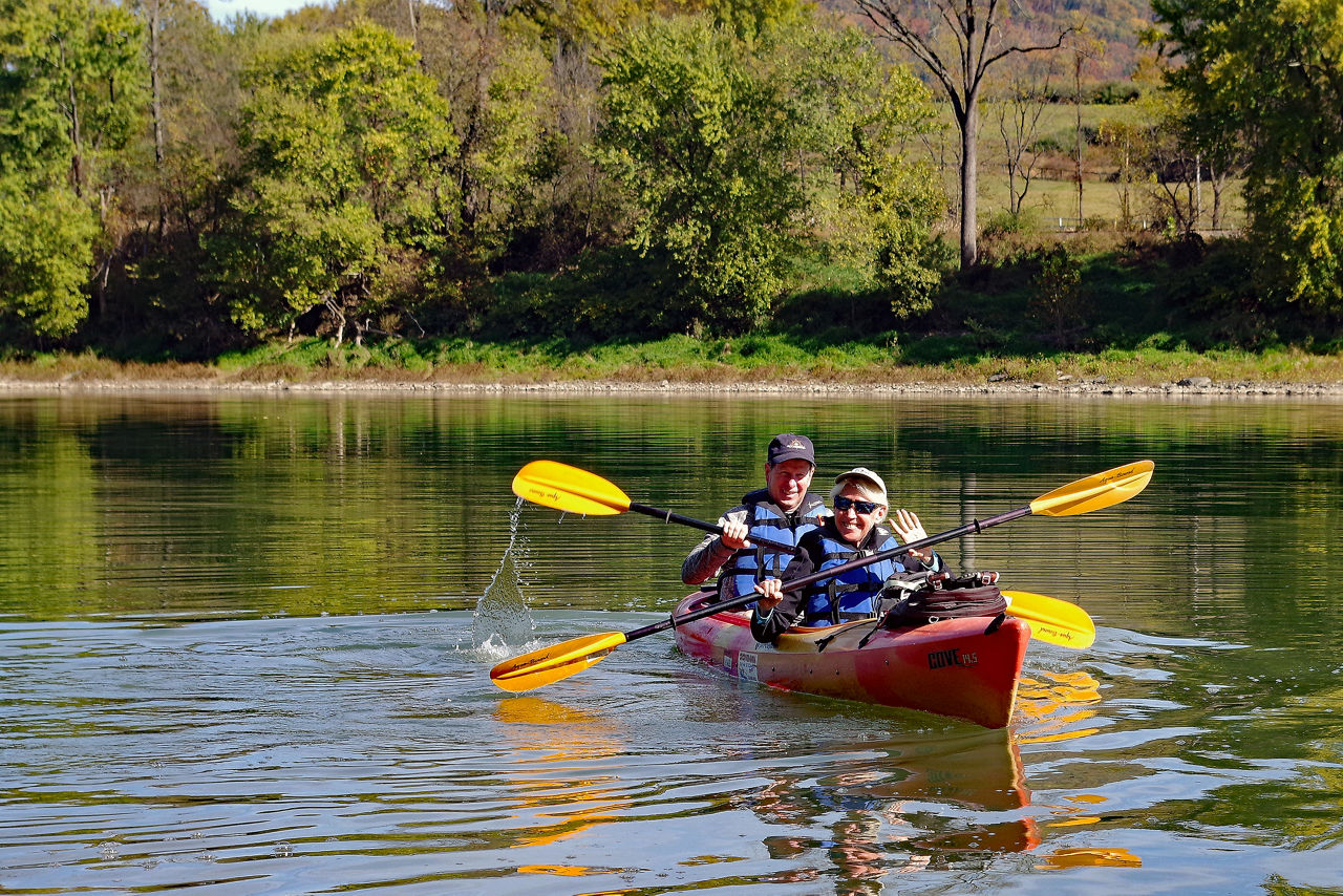 Two people wearing life jackets paddling in a tandem kayak along the North Branch Susquehanna River Water Trail