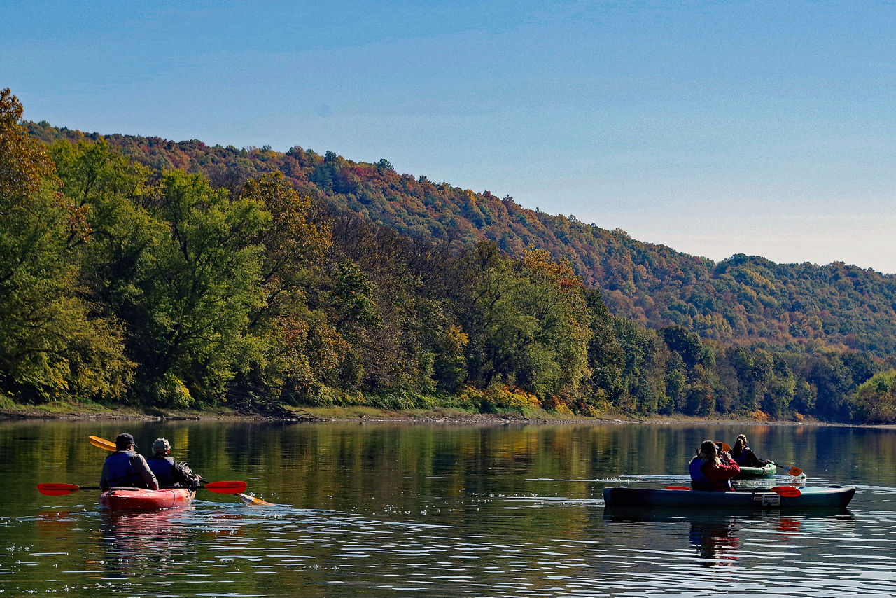 A group of paddlers wearing life jackets while kayaking on the North Branch Susquehanna River Water Trail with fall foliage in the background.