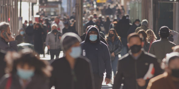 People walk down a street wearing medical masks.