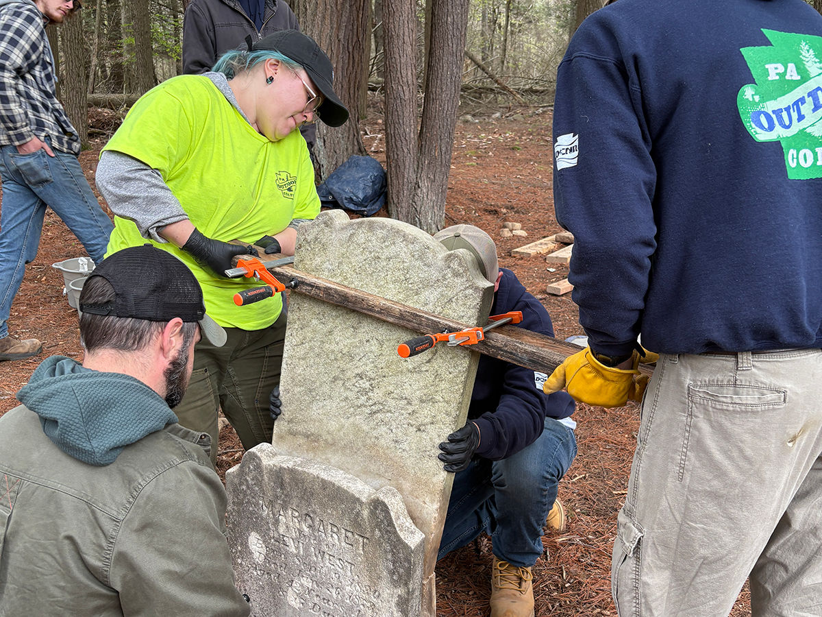 PA Outdoor Corps members work to place a grave marker on a new base.