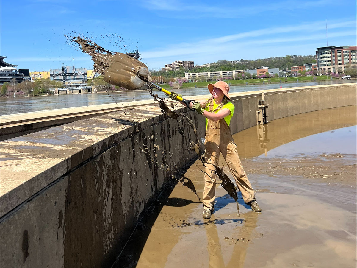 A PA Outdoor Corps member removes mud from the fountain at Point State Park.