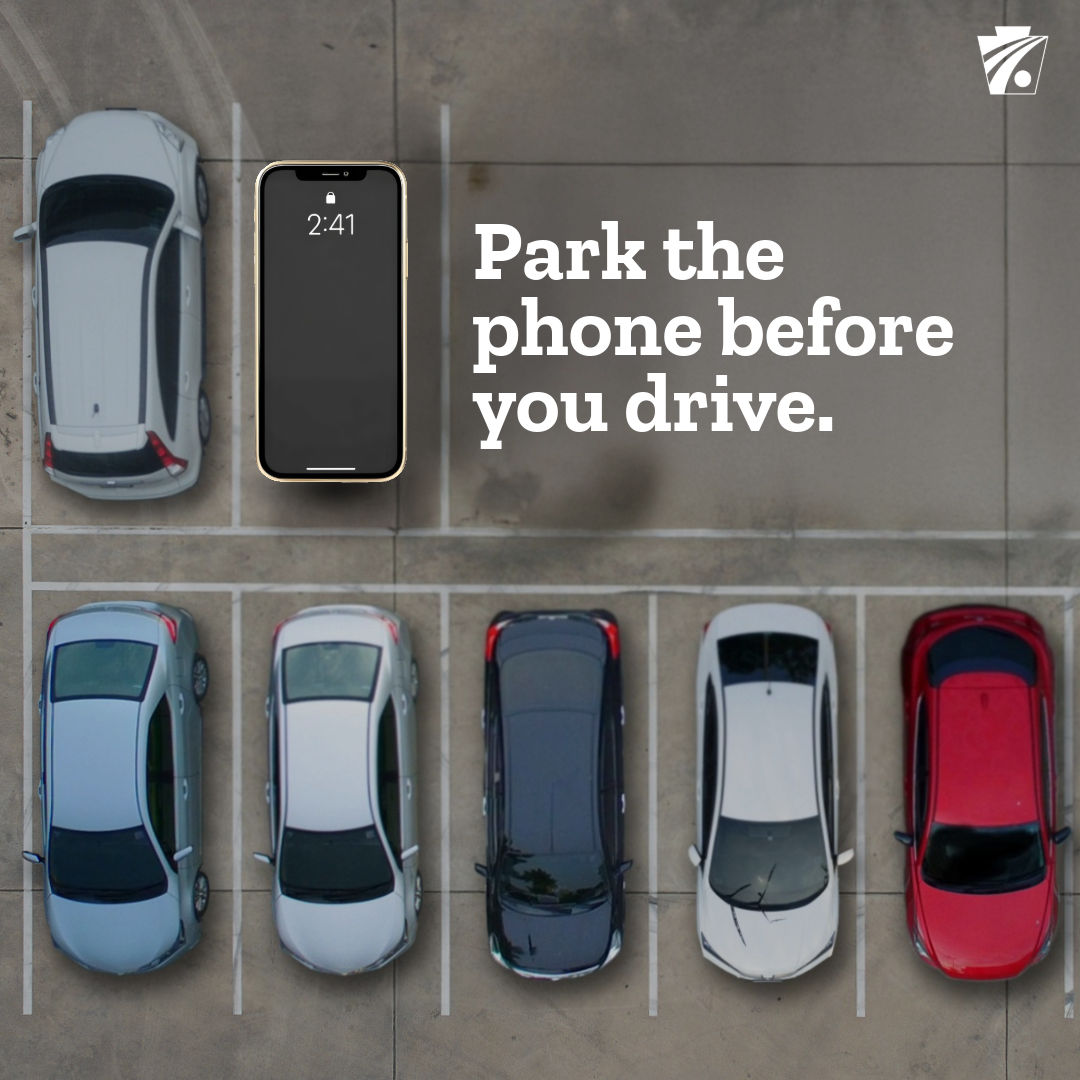 an image of vehicles in a parking lot with an iPhone 'parked' in a spot, white text that reads "Park the phone before you drive"