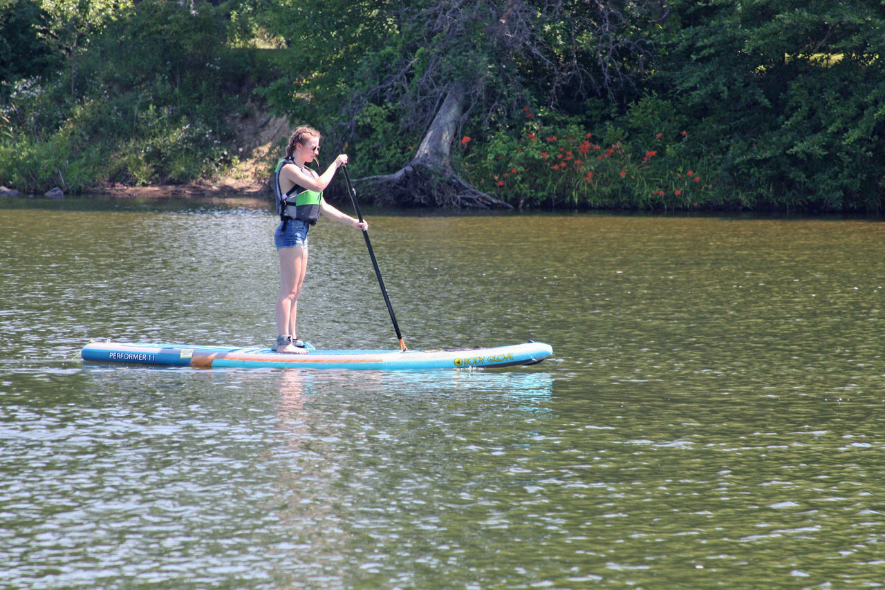 Woman wearing a life jacket, whistle and paddleboard leash while paddleboarding on the Pymatuning Reservoir.