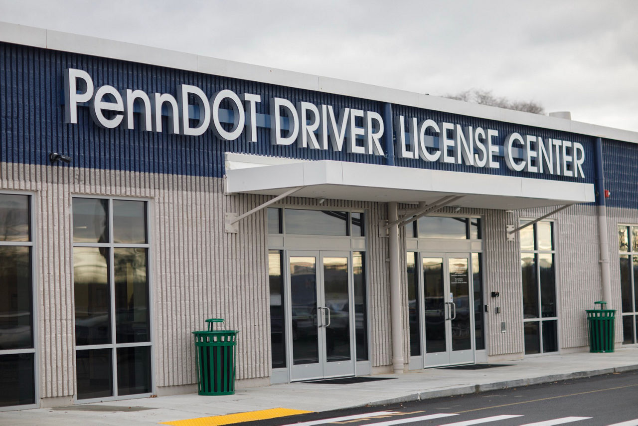 An image of a PennDOT Driver License Center. Large windows sit on either side of two, double-sided doors covered by an awning and the words “PennDOT Driver License Center” above it.