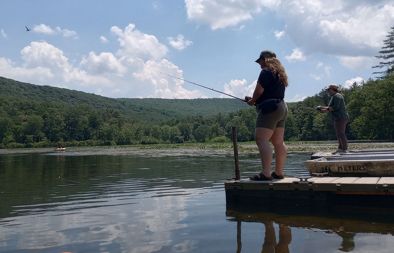 A woman fishing from a dock at a lake