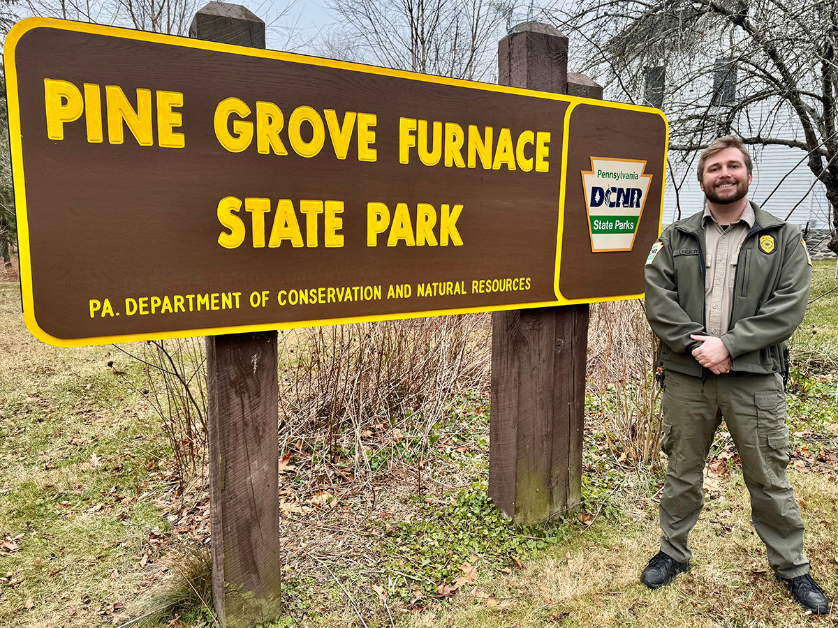 Park Manager Drew Leidich stands in front of the Pine Grove Furnace State Park sign.