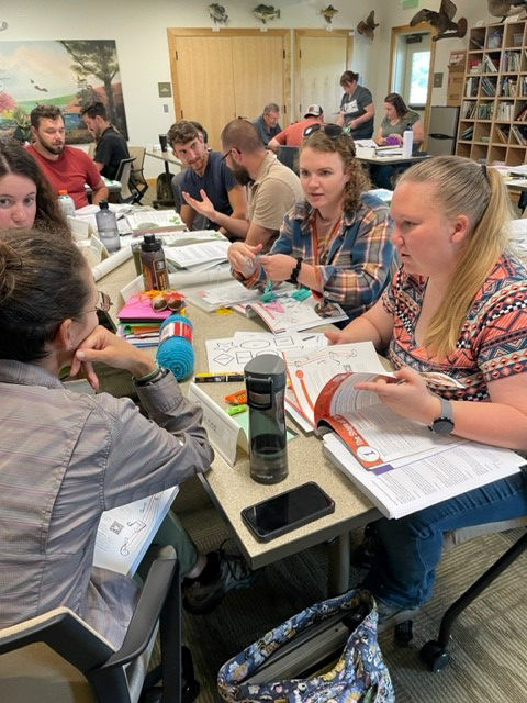 A group of educators sitting at tables with supplies for planning programs