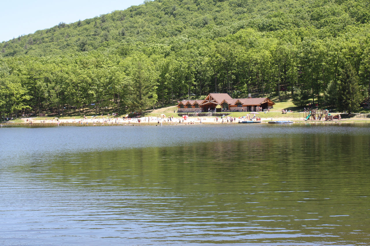 A lake with a swimming area, building, and forest in the background