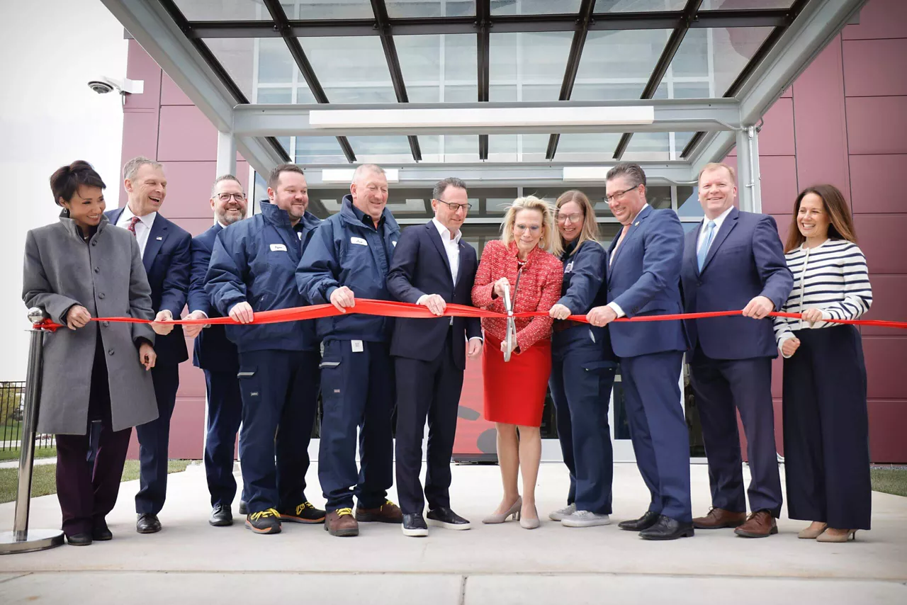 Goveror Josh Shapiro and a group of Hershey company executives cut a ceremonial ribbon outdoors in front of a new manufacturing facility.