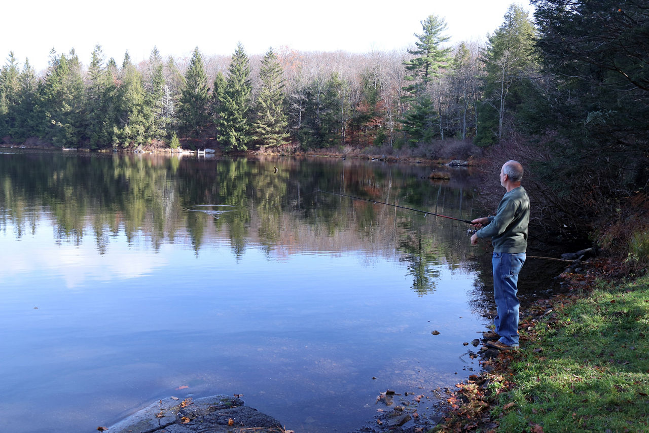 A fisherman on the side of the lake in the early spring