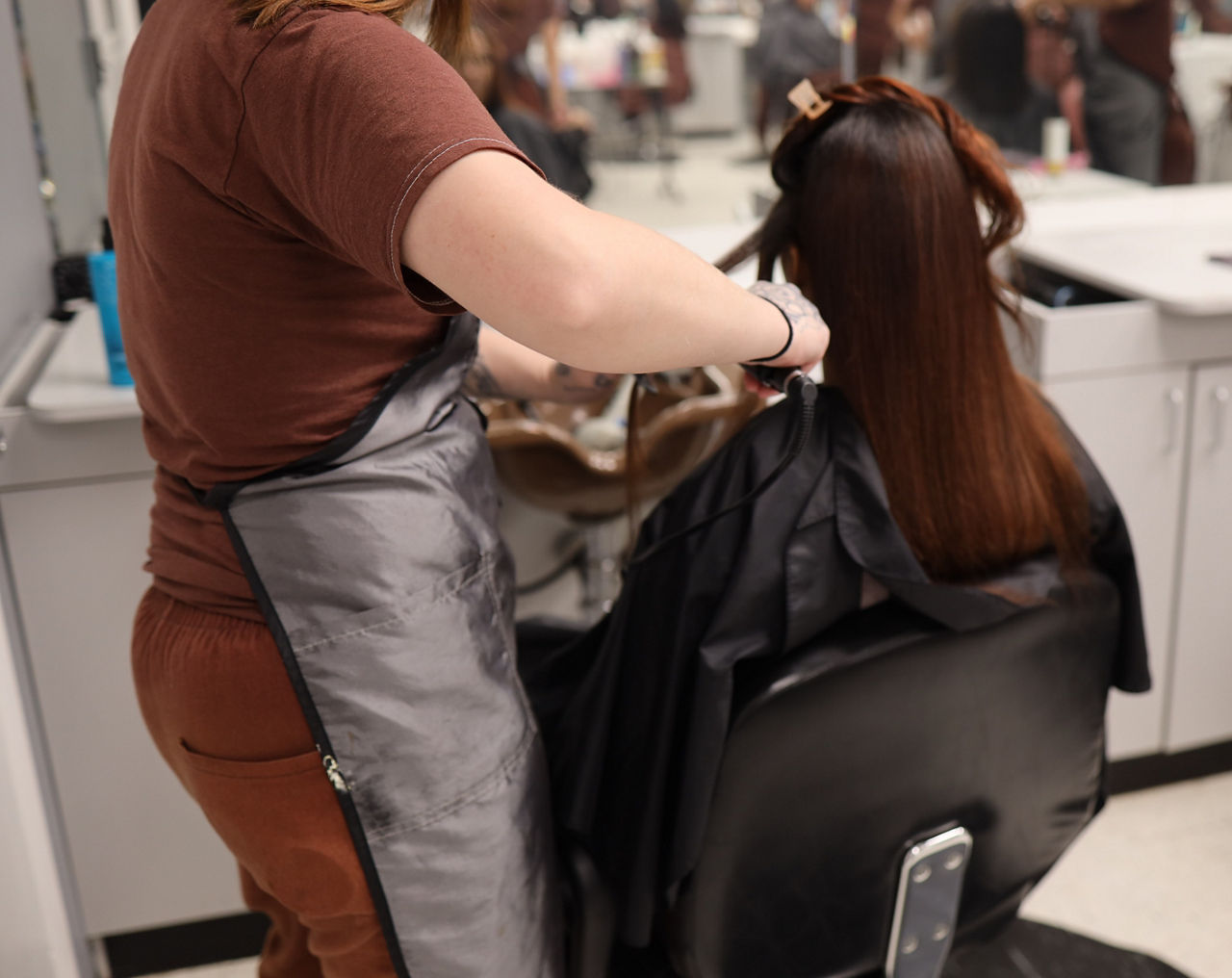 An incarcerated cosmetologist curls the hair of an inmate