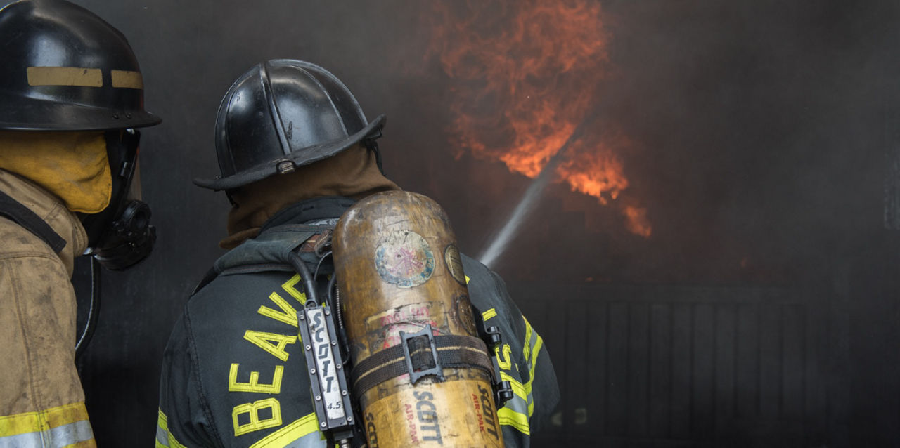 Firefighters using a water hose to battle a fire