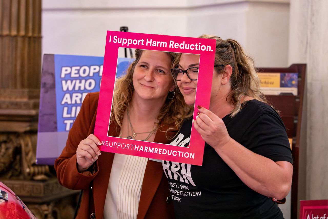 women with photo frame that reads I support harm reduction