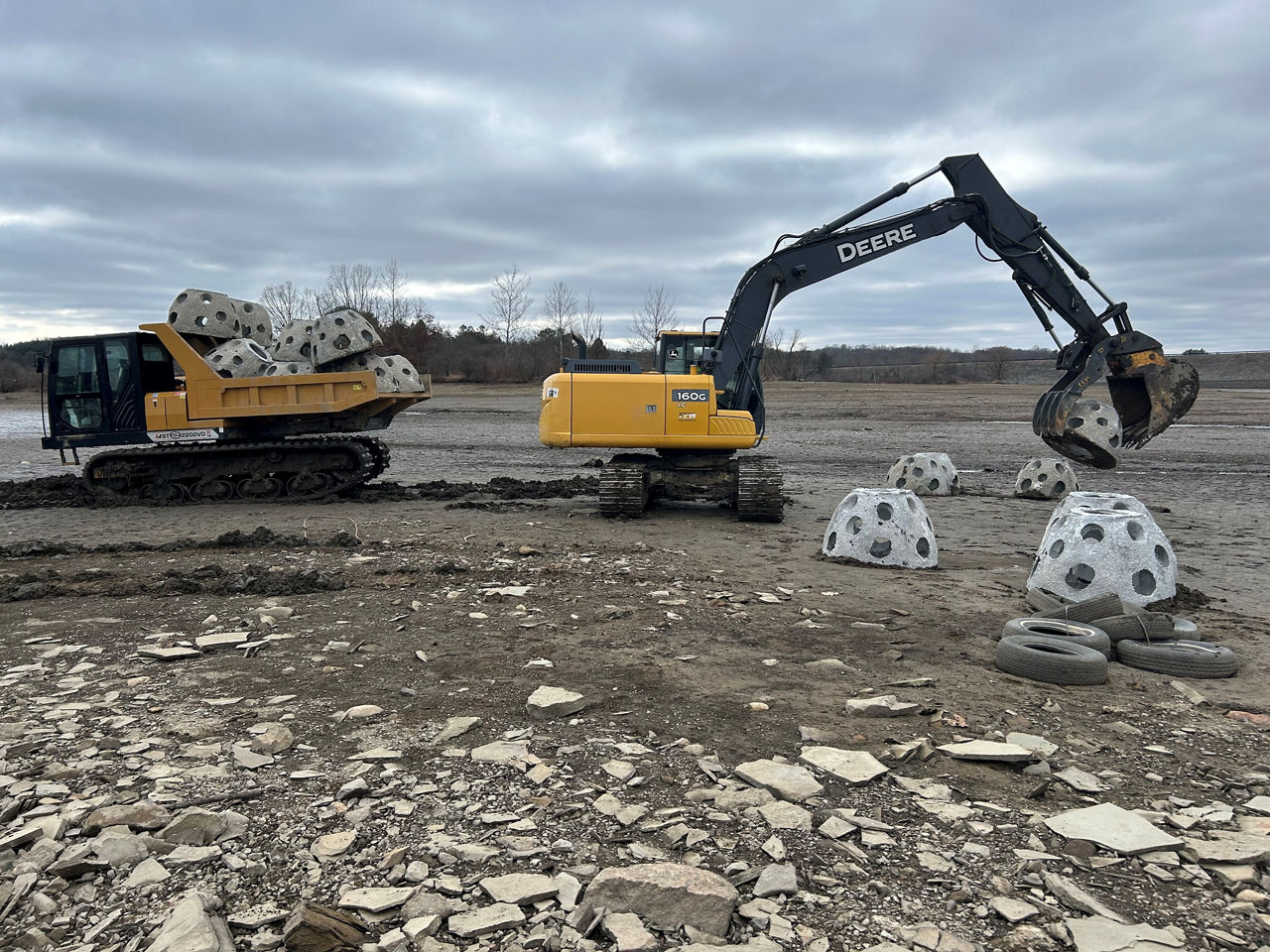 Excavators placing Concrete Reef Balls into the lake bottom of Woodcock Creek Lake for habitat improvement