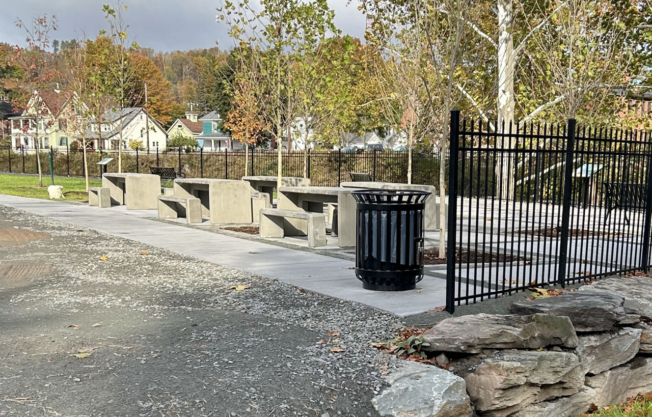 Image of concrete tables and benches constructed along a river for additional seating.