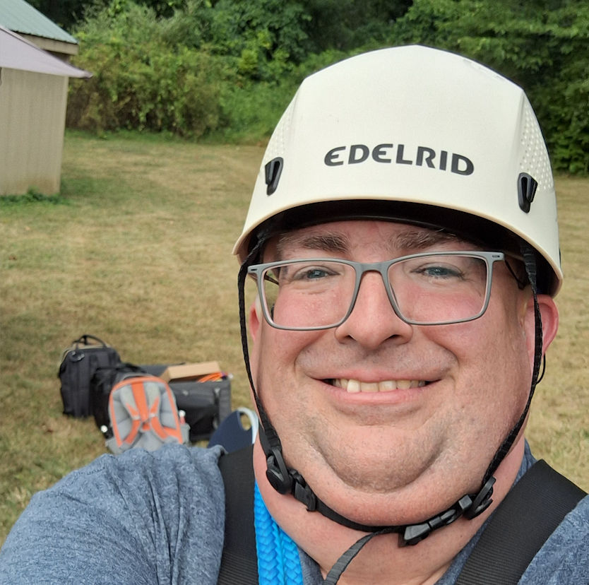 Russ Goddard takes a selfie, wearing a helmet and harness