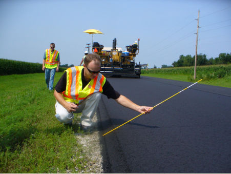 construction worker measuring edge angle of roadway