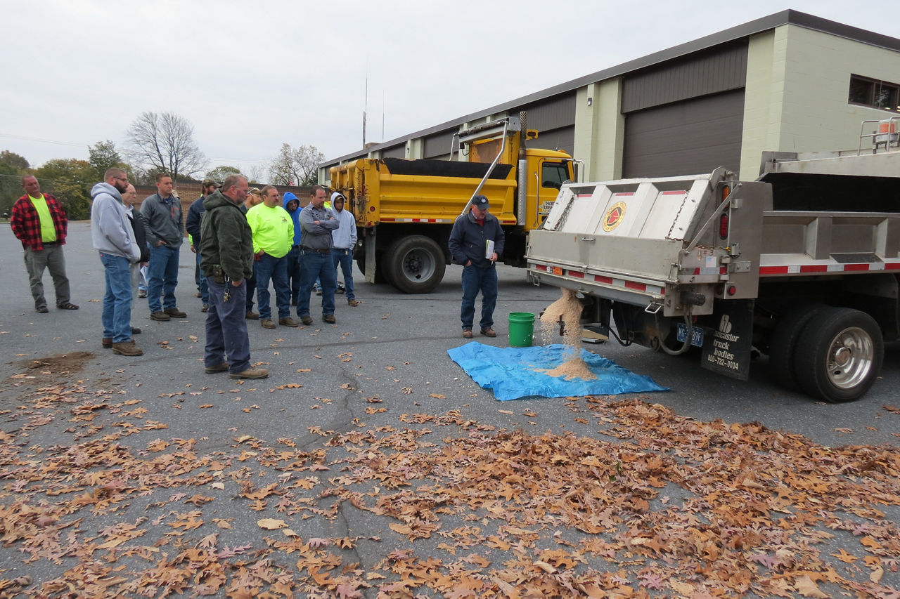 demonstration of salt spreader on back of dump truck.