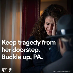 Woman crying with police at her door. Text overlay reads, “Keep tragedy from her doorstep. Buckle up, PA.”