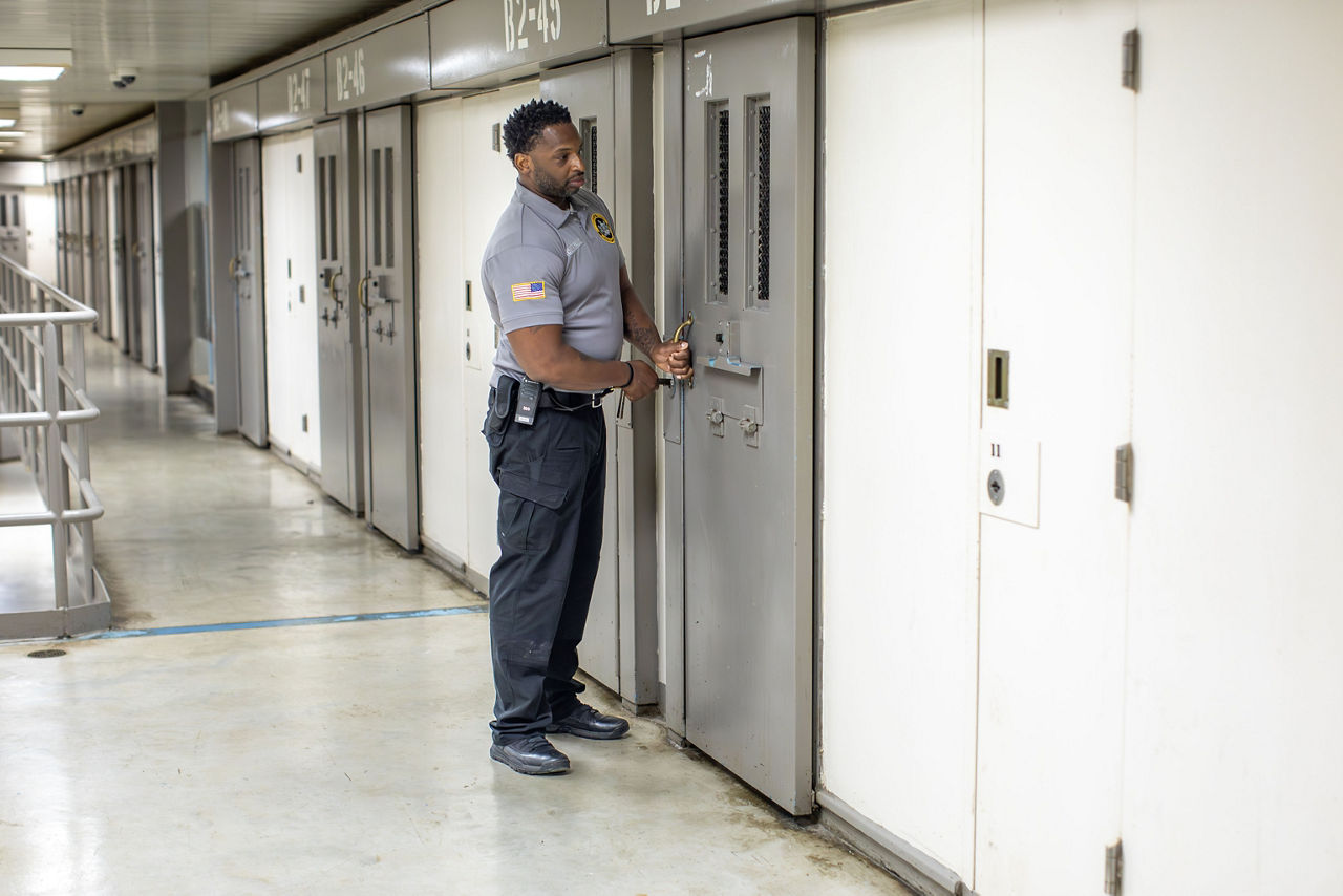 A corrections officer locks a cell door
