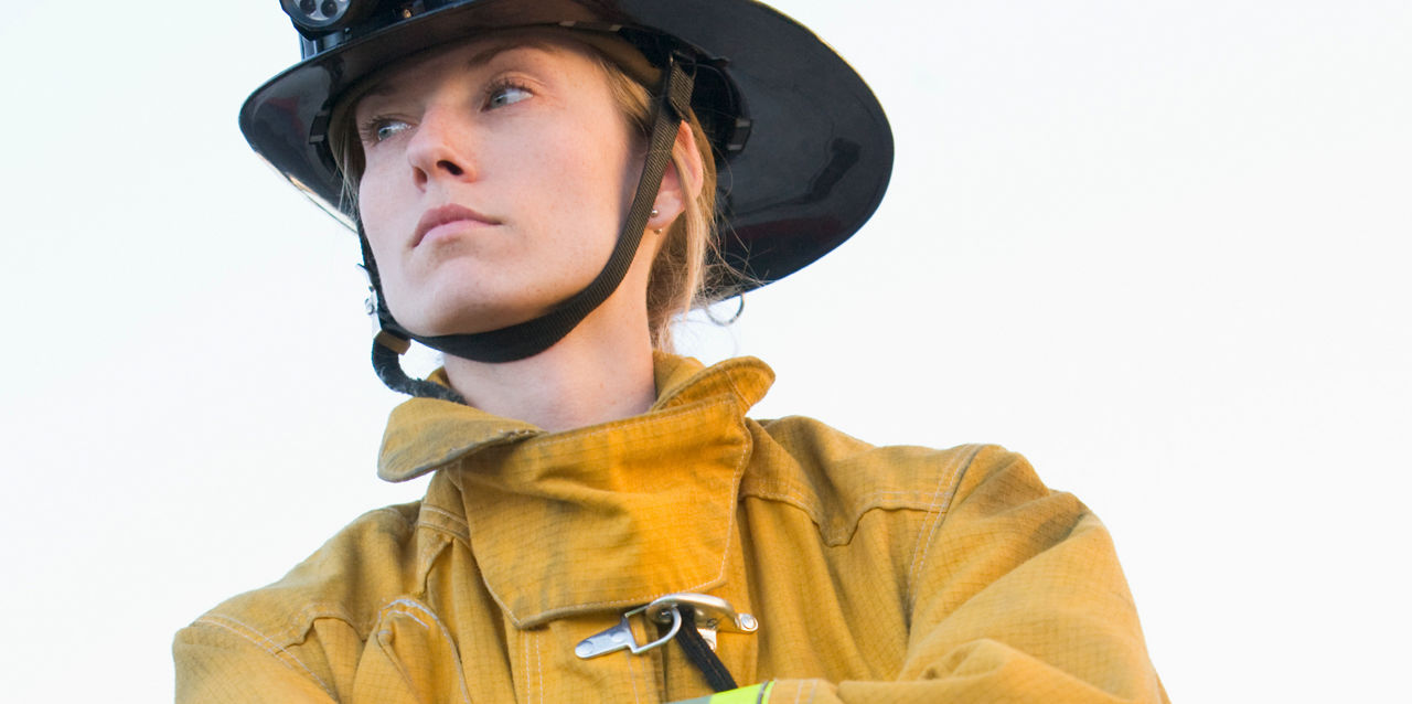 A firefighter looks serious while crossing her arms.