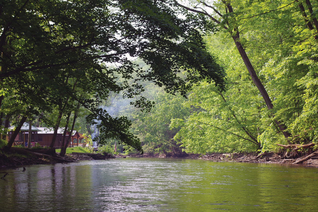 A scenic view of the Shenango River with trees lining both sides of the river bank. 