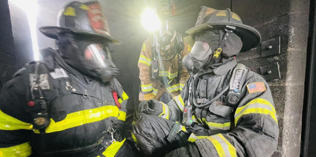A firefighter carries a child who is holding a stuffed bunny.