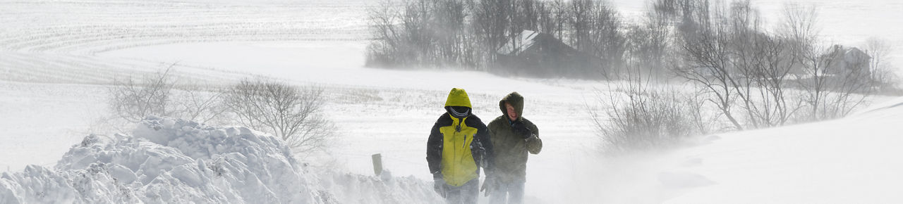 Two people walk through a snowstorm.