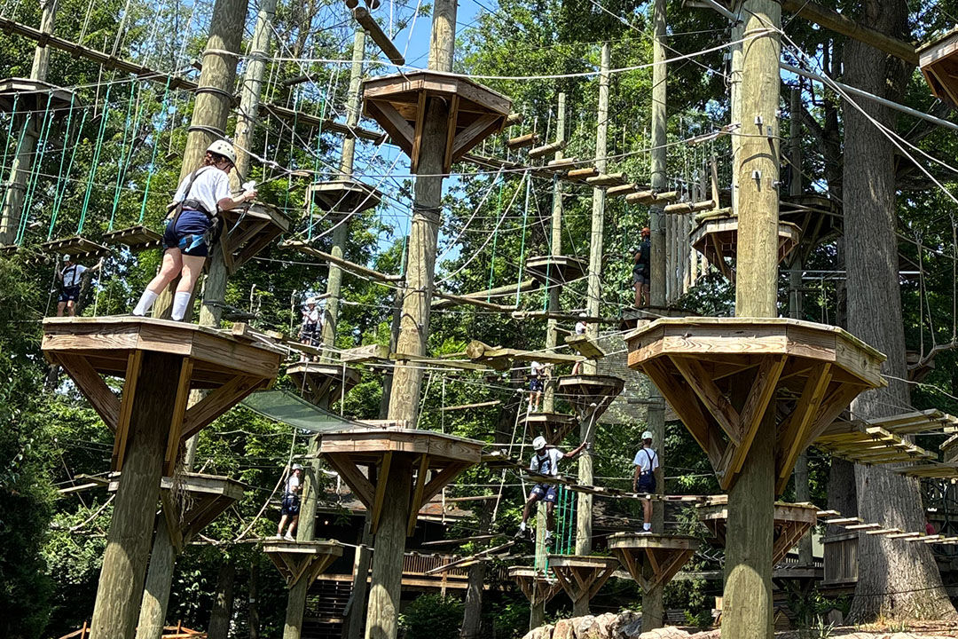 Youths explore a large outdoor rope course 