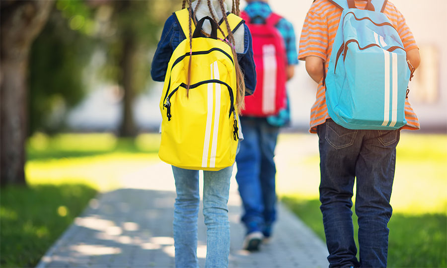Children with rucksacks standing in the park near school