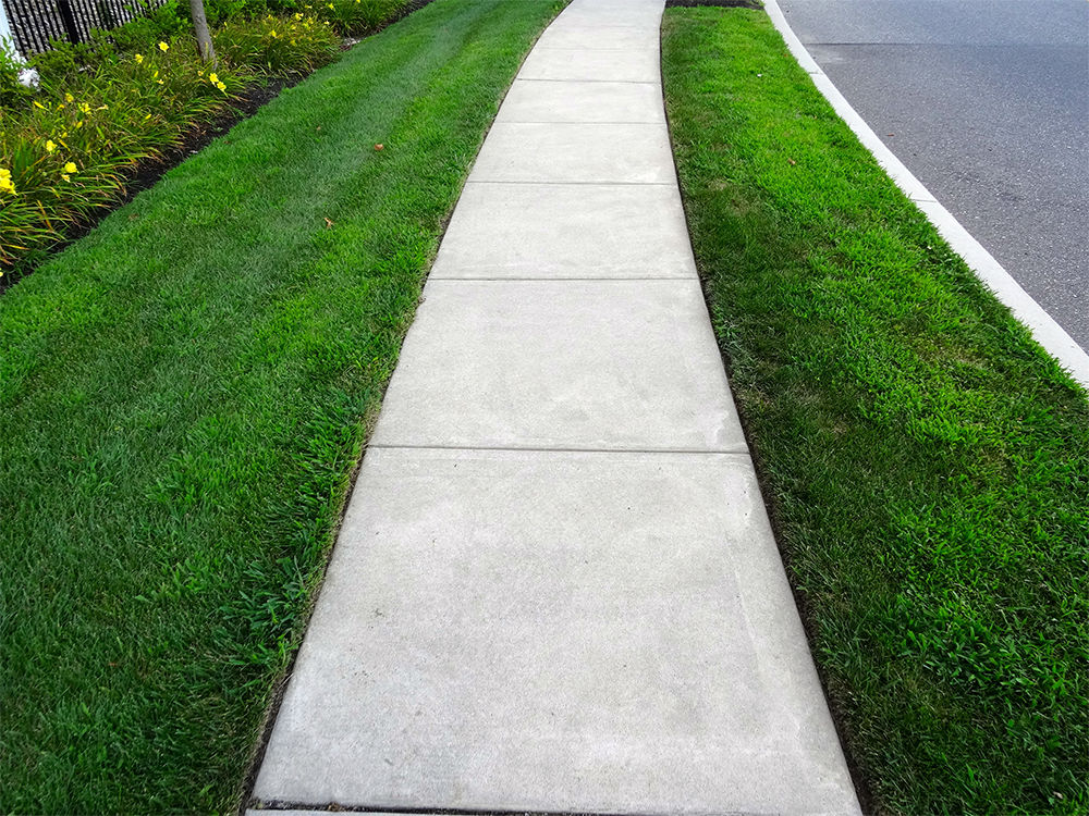 Sidewalk cutting through a neighborhood lawn next to a street