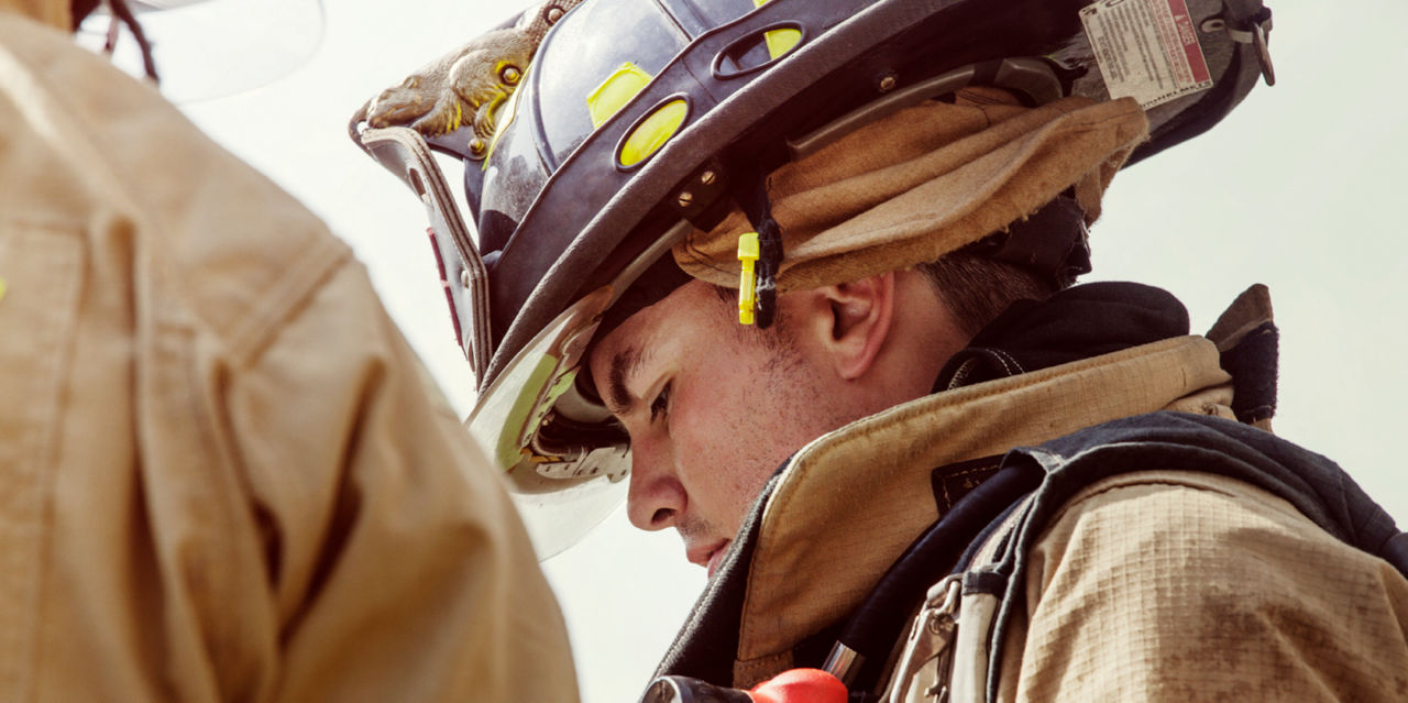 A firefighter in full gear looks down.