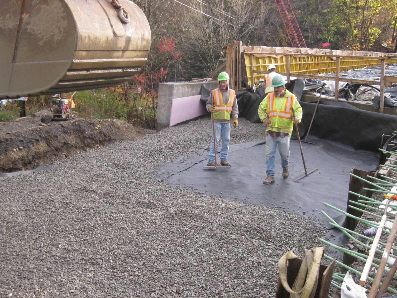 Construction worker spreading gravel over a tarp.