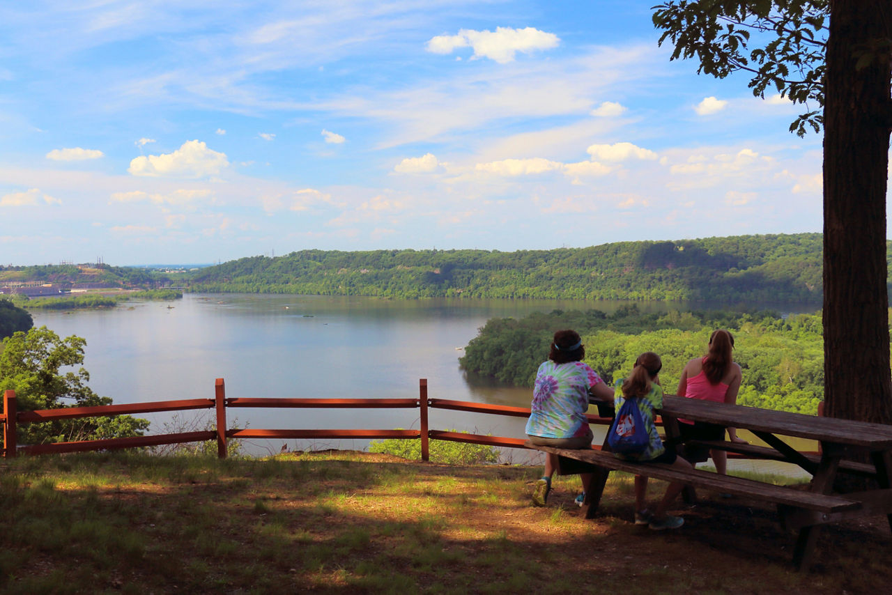 A family sitting at a picnic table overlooking the river and surrounding lands